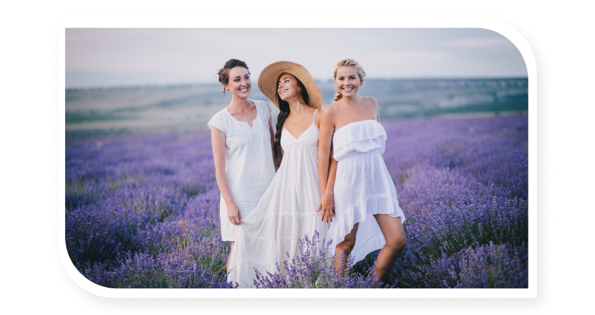 3 girls in white dresses smiling in lavender field