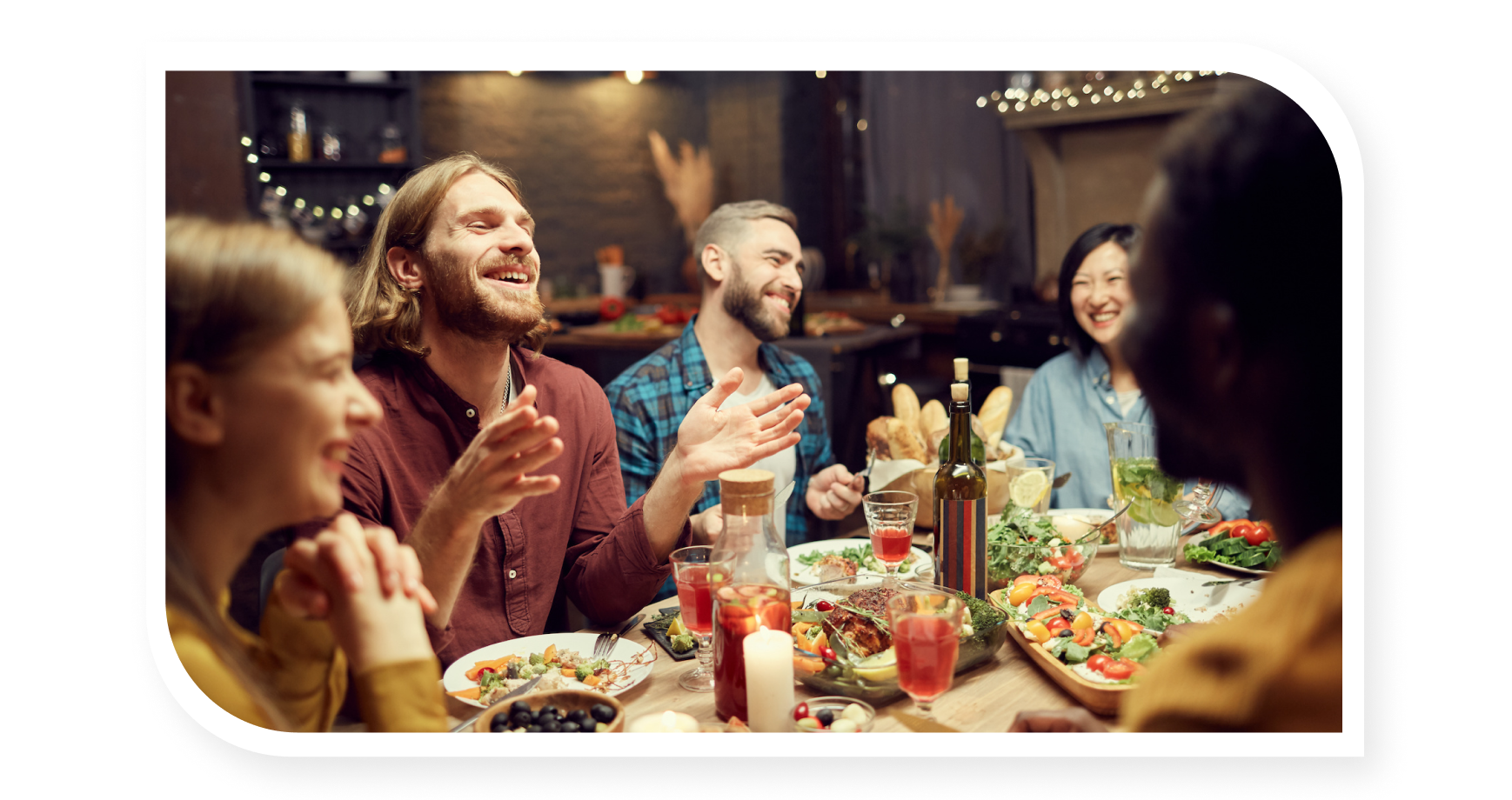 Family laughing and talking around a table with wine and food