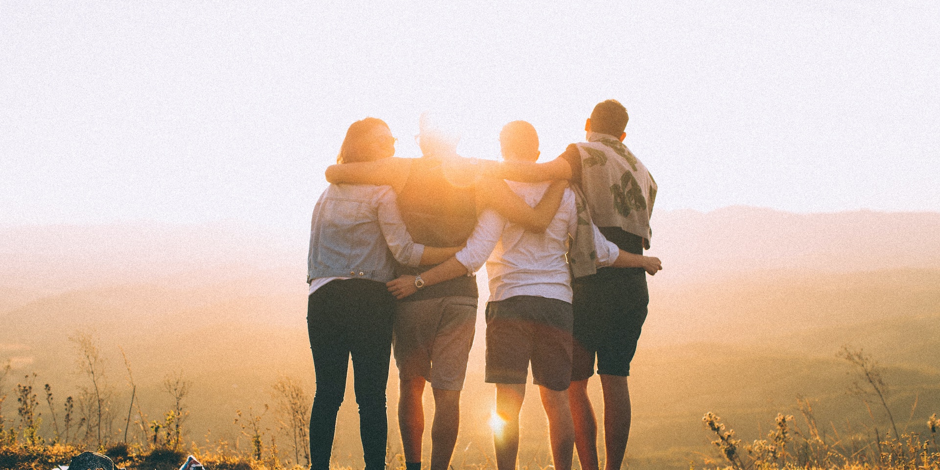 Group of friends hugging during sunset