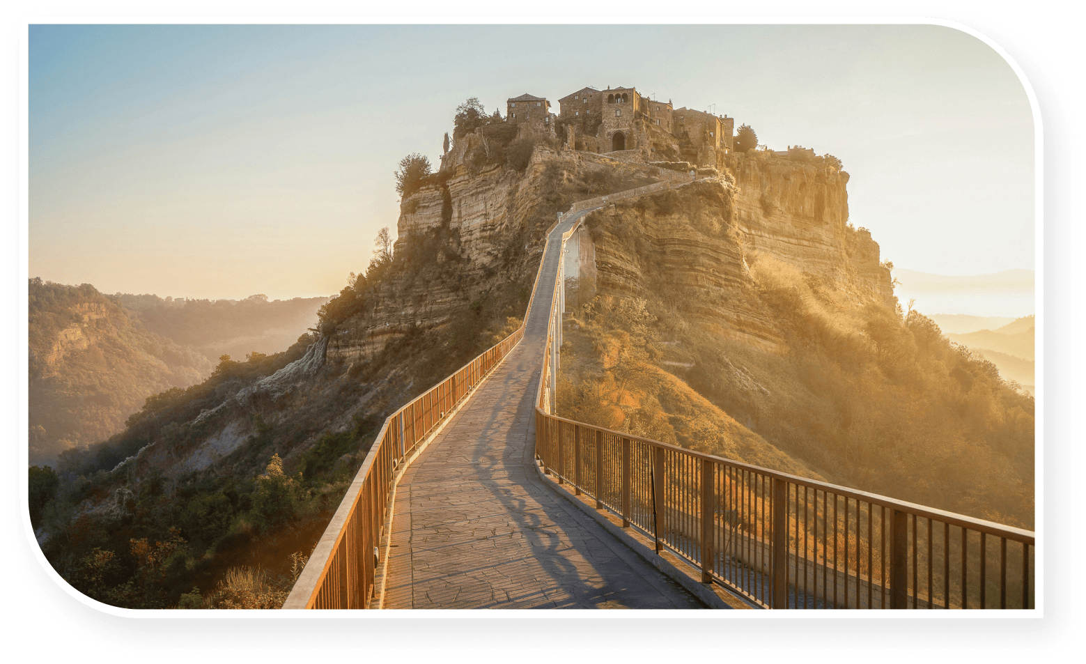 Pathway leading to the ancient hilltop village of Civita di Bagnoregio in Italy, surrounded by dramatic cliffs and bathed in warm sunlight.